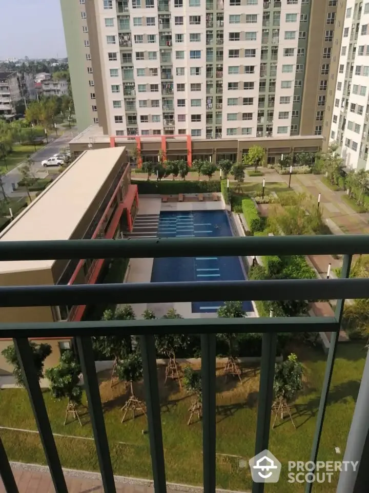 Modern apartment complex with pool view from balcony, lush greenery and urban setting.