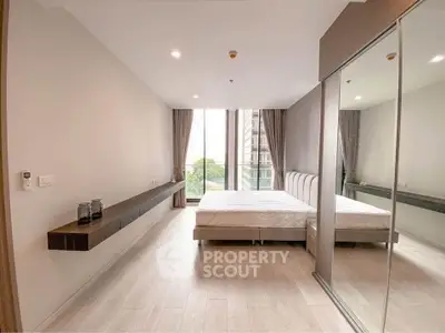Spacious modern bedroom with large windows and mirrored closet in urban apartment.