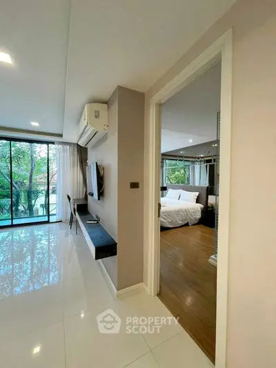 Modern apartment interior with spacious living room and bedroom, featuring large windows and elegant decor.