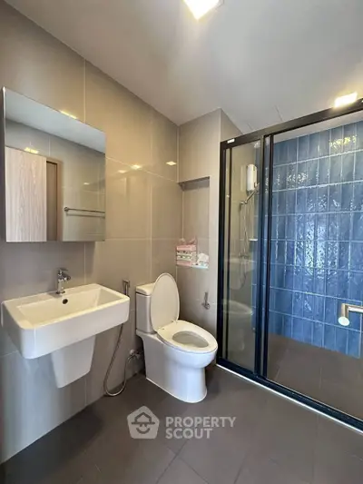 Modern bathroom with sleek design, featuring a glass shower enclosure and stylish fixtures.