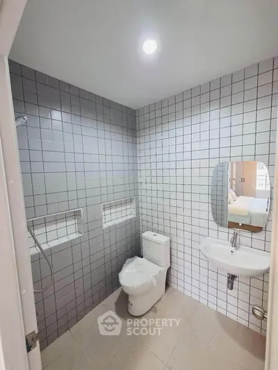 Modern bathroom with sleek tiles and compact fixtures in a contemporary apartment.