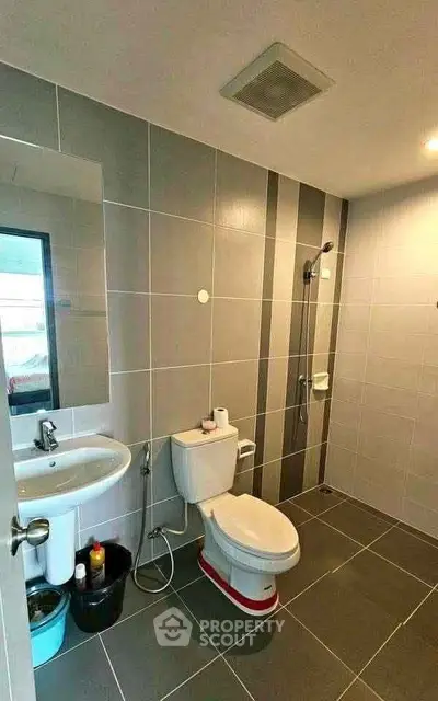Modern bathroom with sleek gray tiles and contemporary fixtures in a stylish apartment.