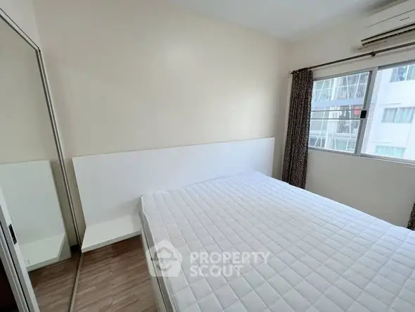 Bright bedroom with large window and mirrored closet in modern apartment.