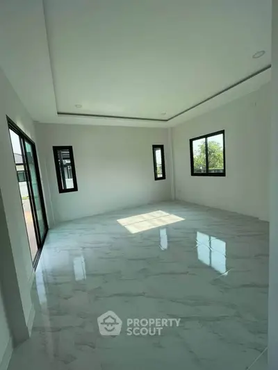 Spacious and bright living room with large windows and marble flooring