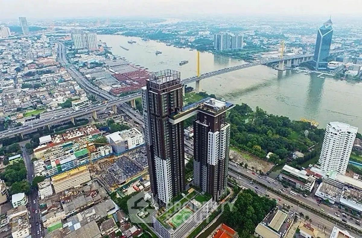 Stunning aerial view of modern high-rise buildings by the river, showcasing urban skyline and lush greenery.