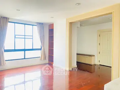 Spacious living room with large window and hardwood floors in modern apartment