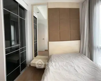 Modern bedroom with stylish headboard and mirrored wardrobe in a cozy apartment.