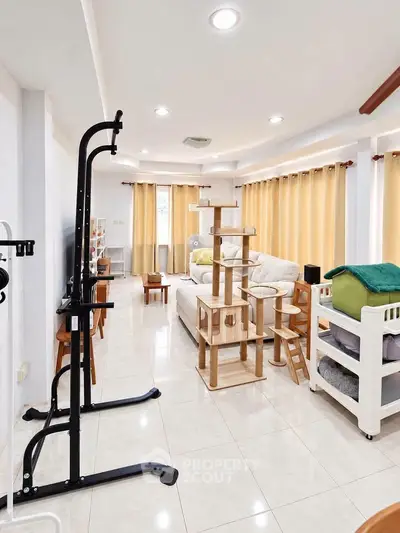 Spacious living room with modern furniture and cat tree, perfect for pet lovers.