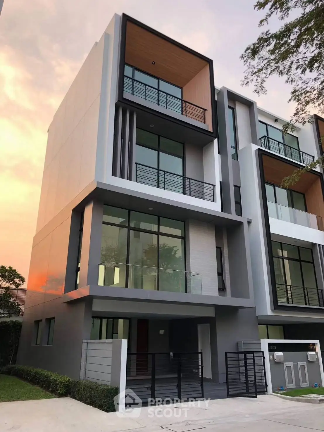 Modern multi-story townhouse with sleek design and large windows at sunset.