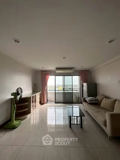 Spacious living room with large windows and city view, featuring modern furniture and elegant decor.