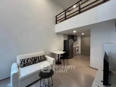 Modern loft-style living room with mezzanine, sleek furniture, and open kitchen layout.