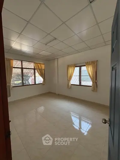 Spacious empty room with tiled floor and large windows, perfect for customization.