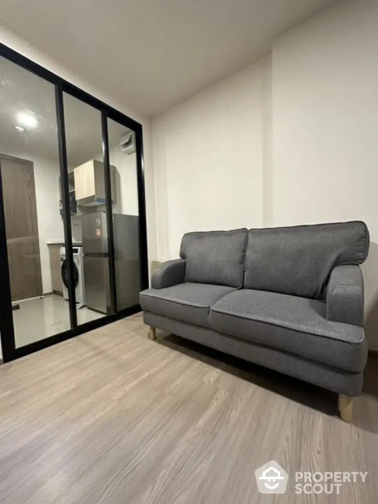 Modern living room with sleek glass partition and cozy gray sofa