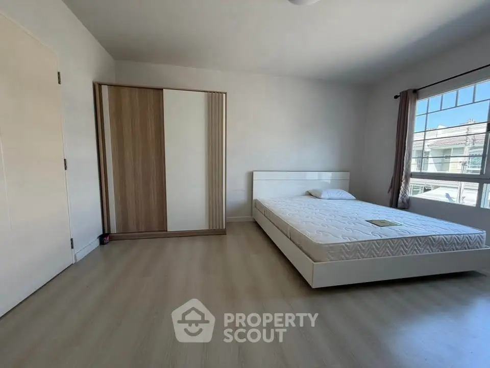 Spacious bedroom with modern minimalist design and large window for natural light.