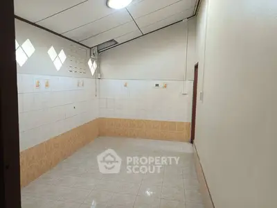 Spacious tiled room with high ceiling and natural light
