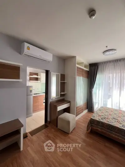 Modern bedroom with wooden flooring and natural light, featuring a cozy bed and stylish furniture.