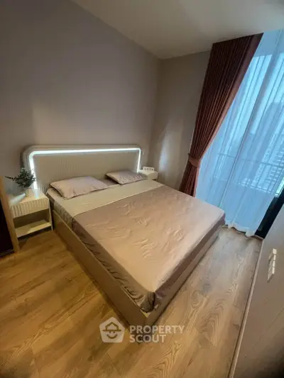 Modern bedroom with stylish lighting and floor-to-ceiling window in a high-rise apartment.