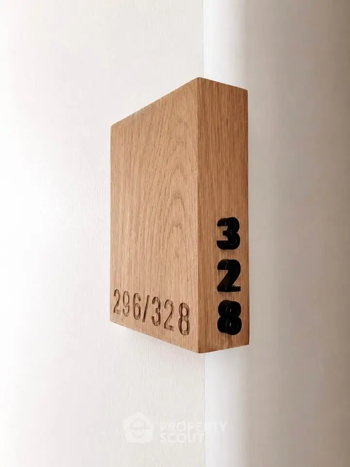 Modern wooden room number sign on a white wall, showcasing minimalist design in real estate interiors.