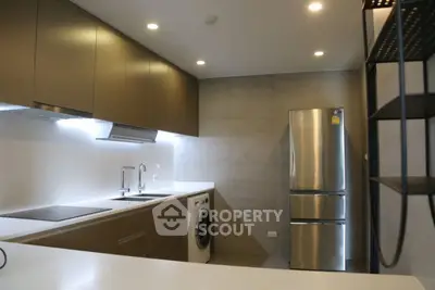 Modern kitchen with sleek cabinets, stainless steel fridge, and built-in washing machine.