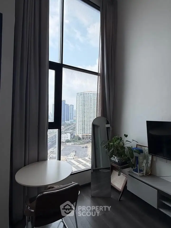 Modern living room with floor-to-ceiling windows offering stunning city views, sleek furniture, and elegant decor.