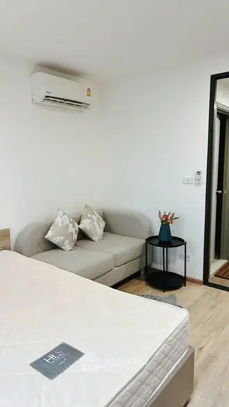 Cozy bedroom with modern decor and air conditioning, featuring a comfortable sofa and stylish side table.