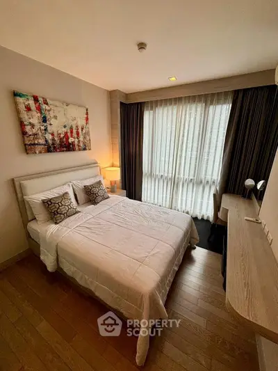 Cozy bedroom with modern decor and large window for natural light.