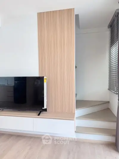 Modern living room with sleek TV setup and stylish staircase design