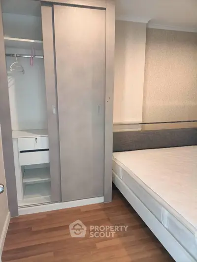 Modern bedroom with built-in wardrobe and comfortable mattress on wooden flooring.