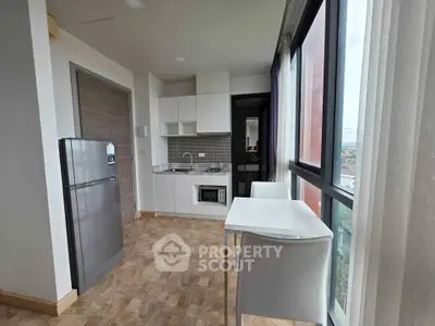 Modern kitchen with sleek appliances and dining area in a bright apartment with large windows.