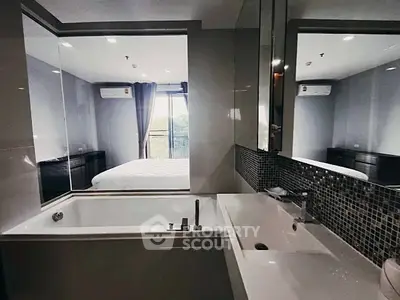 Modern bathroom with bathtub and sleek design overlooking a bedroom with natural light.
