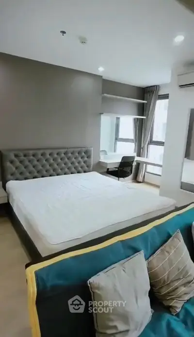 Modern bedroom with stylish bed, cozy seating, and workspace in a bright apartment.