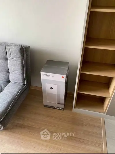Modern living room with stylish grey sofa and wooden shelving unit on sleek wooden flooring.