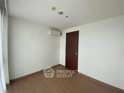 Spacious empty room with wooden flooring and air conditioning, perfect for customization.