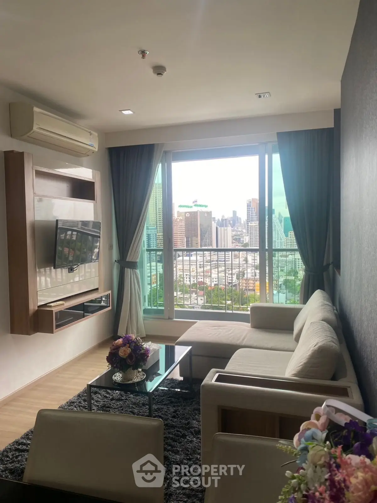 Modern living room with city view, elegant decor, and cozy seating area.