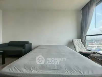 Spacious bedroom with city view, featuring a cozy bed, modern sofa, and large window for natural light.