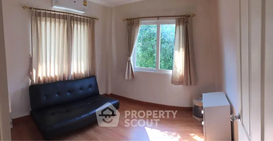 Cozy living room with black sofa and large window offering natural light