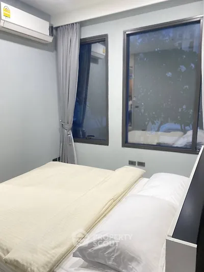 Cozy bedroom with large windows and modern air conditioning unit