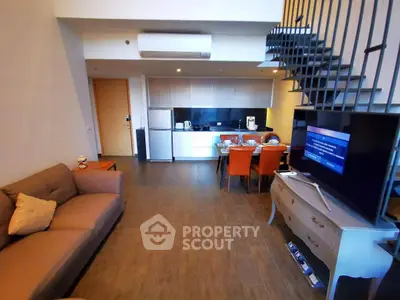 Modern open-plan living room with kitchen and stylish staircase in a contemporary apartment.