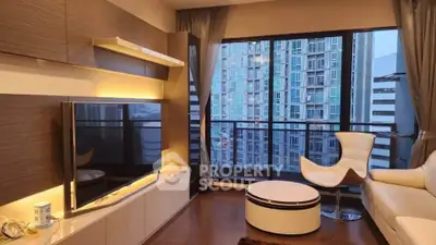 Modern living room with large TV, stylish furniture, and city view from balcony.