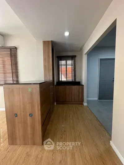Modern interior with wooden flooring and cabinetry, featuring a sleek design and ample natural light.