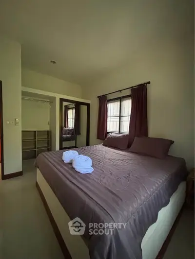 Cozy bedroom with large bed and natural light, perfect for relaxation.
