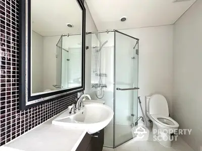 Modern bathroom with glass shower and sleek fixtures in contemporary home.