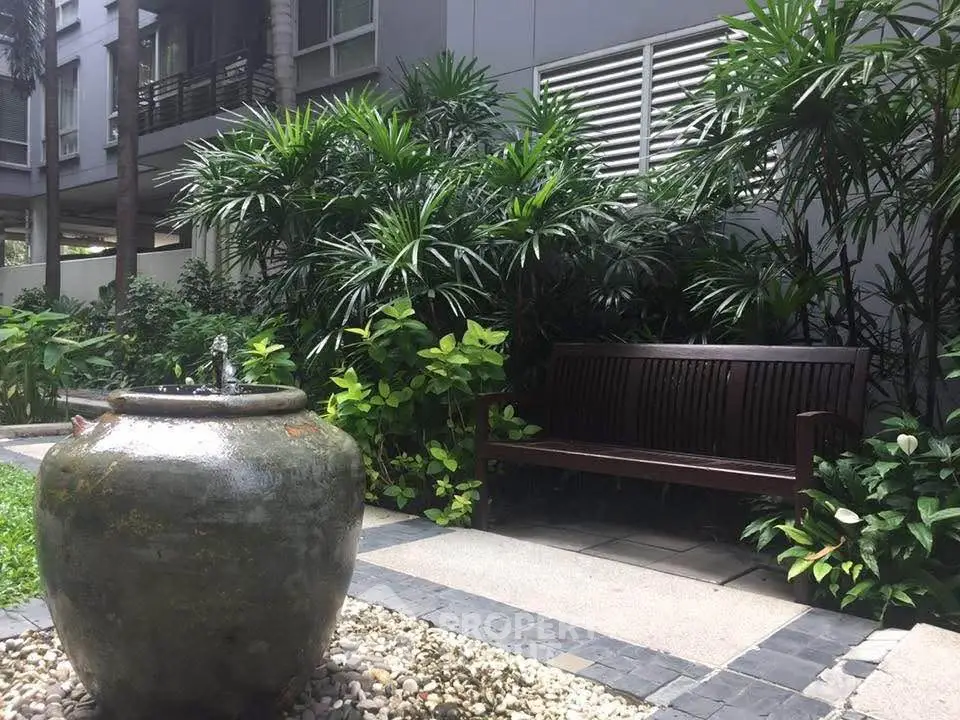 Serene garden area with lush greenery and a stylish water feature in a modern residential complex.