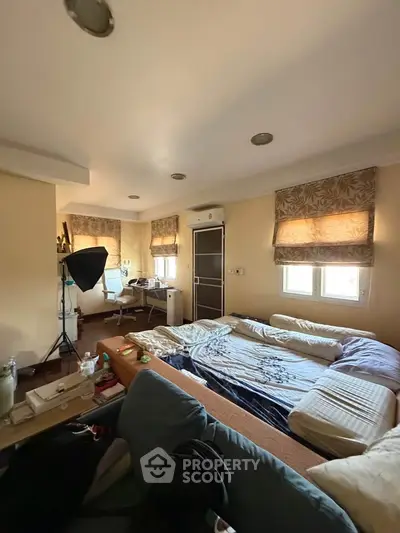 Spacious bedroom with cozy seating and natural light, ideal for relaxation and work-from-home setup.