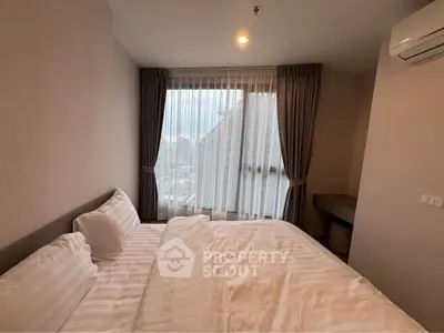 Cozy bedroom with large window and modern air conditioning unit, offering a serene and comfortable living space.
