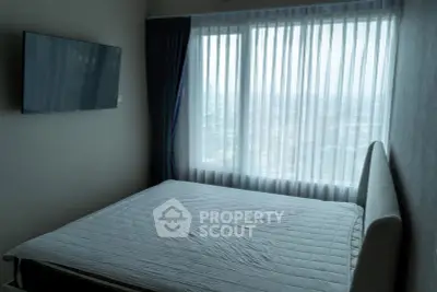 Modern bedroom with large window and wall-mounted TV, offering a serene city view.