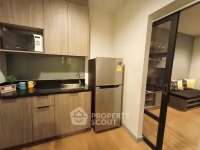 Modern kitchen with sleek cabinetry and stainless steel fridge in cozy apartment
