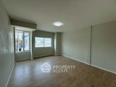 Spacious empty room with large windows and wooden flooring, perfect for customization.