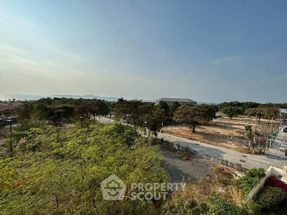 Scenic view from a high vantage point overlooking lush greenery and distant buildings, ideal for real estate development.