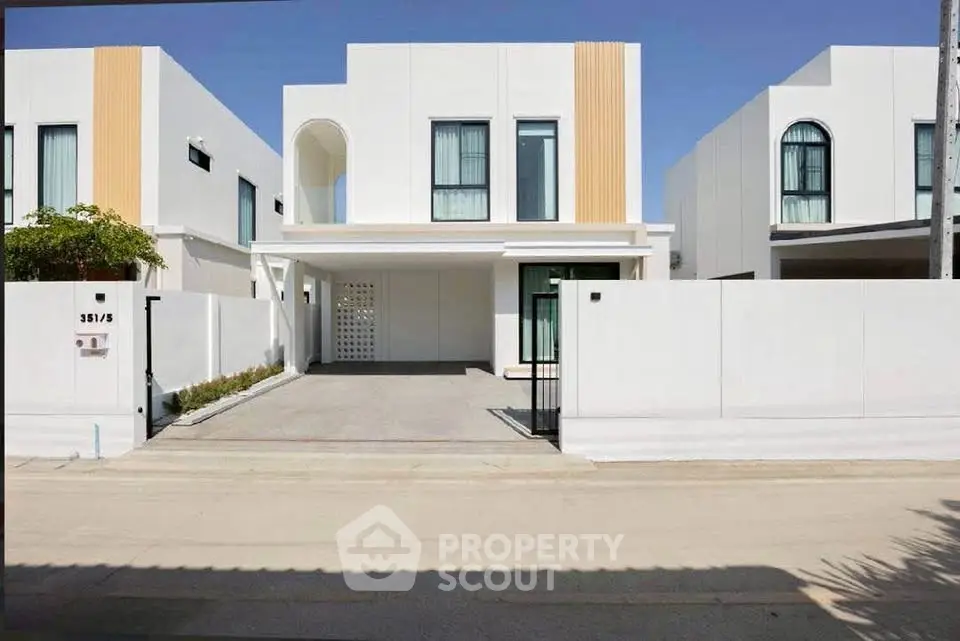 Modern white minimalist house with driveway and clean architectural lines.